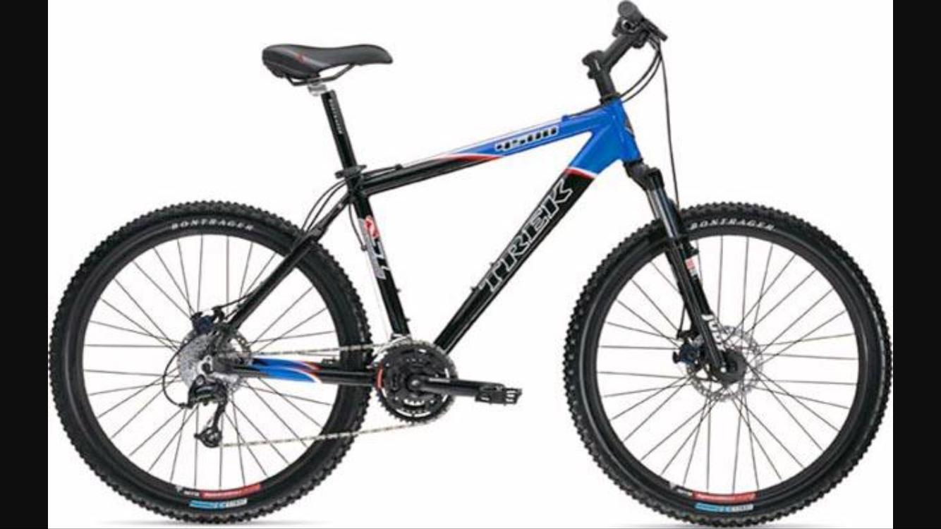 Trek 4500: A blue and black Trek mountain bike, featuring a sturdy frame, thick tires designed for off-road trails, and a prominent suspension fork. The bike is shown from the side, highlighting its geometric design and gear components.