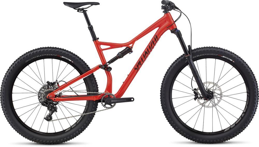Specialized Stumpjumper FSR comp carbon 650B: A vibrant red mountain bike with a sleek frame design, punctuated by the word "Specialized" in bold black letters. The bike features wide, rugged tires for excellent traction, a front suspension fork, and a rear gear system. It's positioned on a neutral background, highlighting its details and sporty aesthetics.