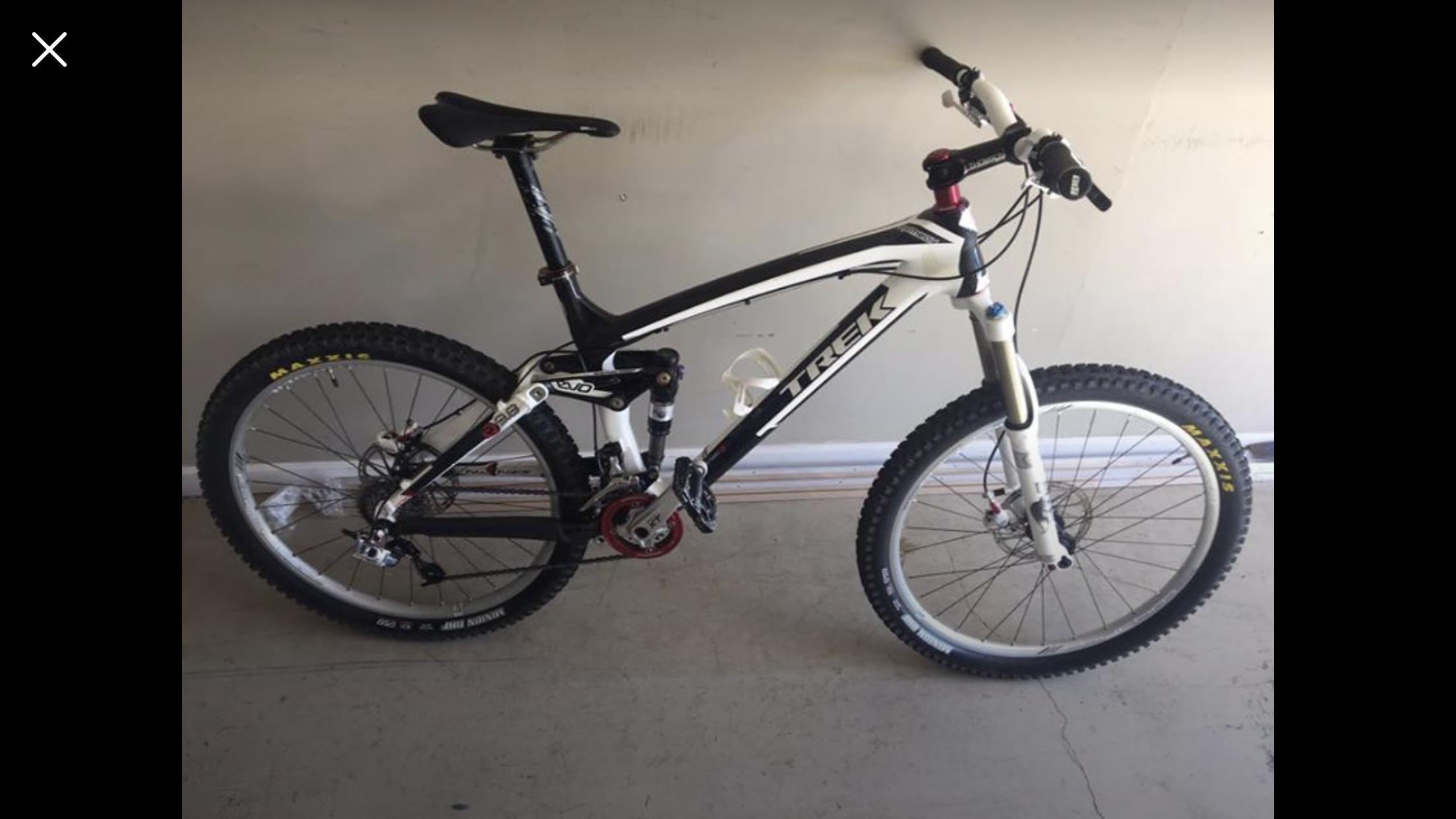 Trek Remedy 9.8 27.5/650b: A black and white mountain bike with wide, knobby tires and a sturdy frame, positioned against a plain wall. The bike features front suspension, disc brakes, and a prominent brand logo.