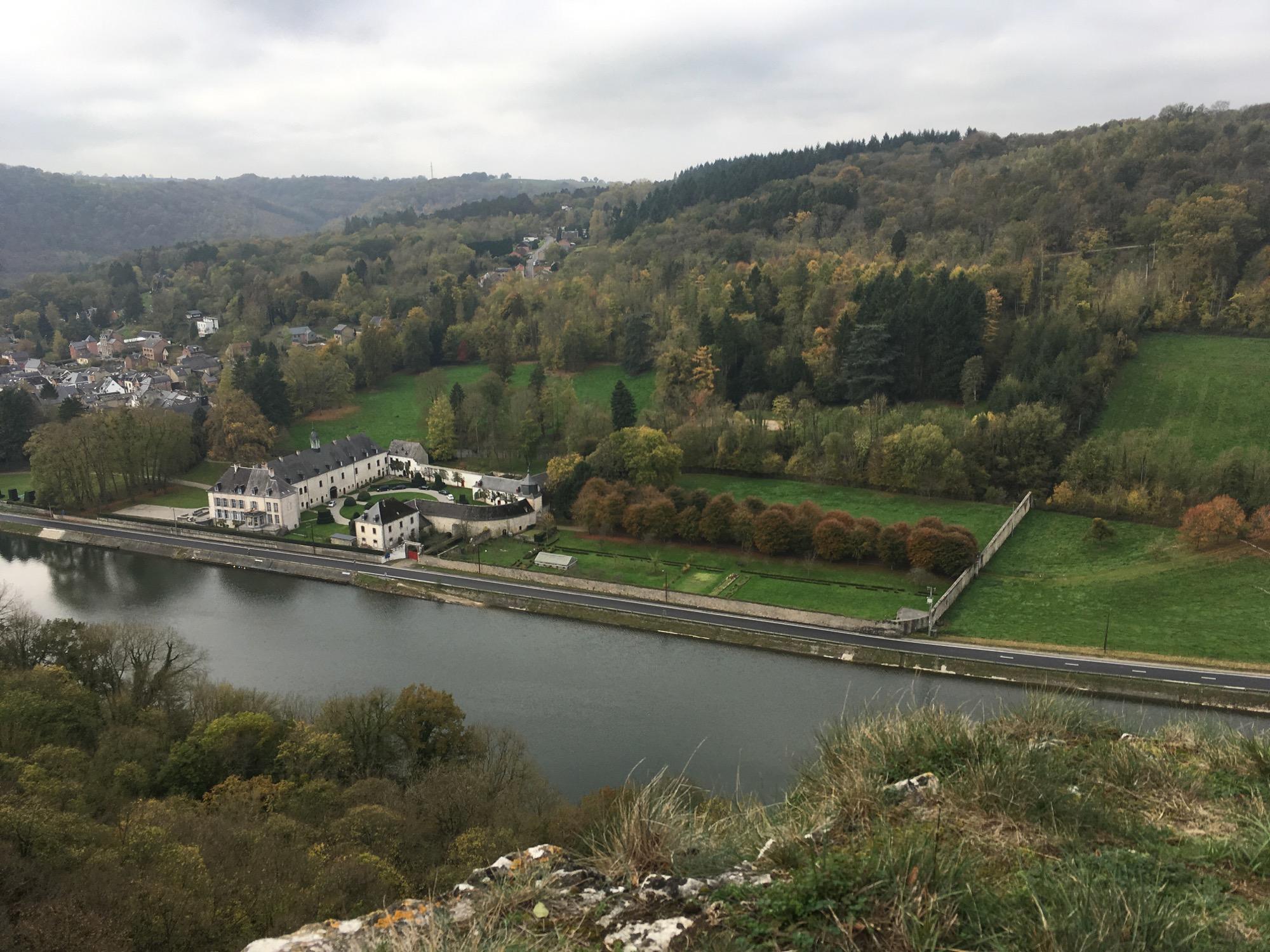 Aerial view of a river bordered by lush green hills, featuring residential buildings along the water