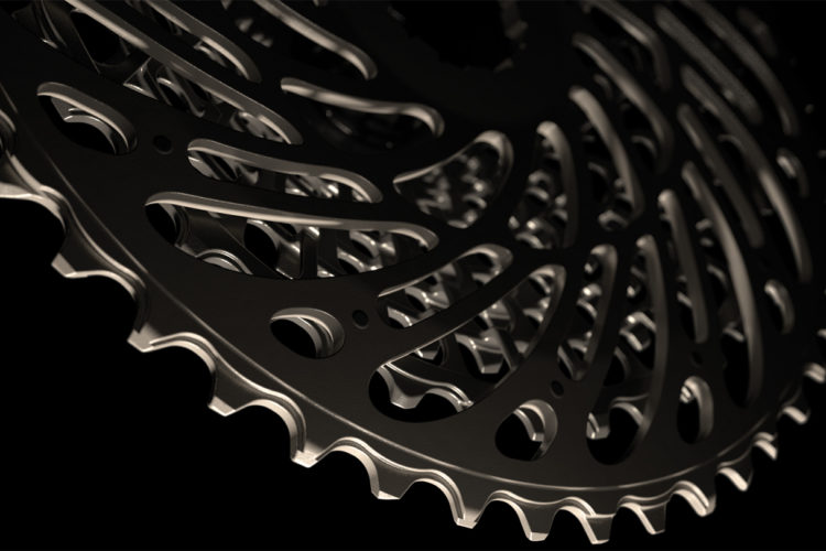 Close-up image of a bicycle cassette, showcasing its intricate design with layered gear teeth and cutouts against a black background. The shiny metallic surface highlights the detailed craftsmanship of the cycling component.