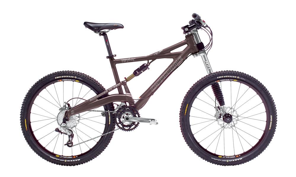 Cannondale Prophet 5: A mountain bike with a brown frame, front suspension, and knobby tires, displayed on a white background. The bike features a black seat, multiple gears, and disk brakes, showcasing its design for off-road biking.