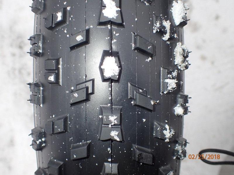 CHAOYANG Big Daddy 26" X 4.9 120TPI: Close-up view of a snow tire with deep tread patterns and some snow particles on the surface, suitable for traction in winter conditions.