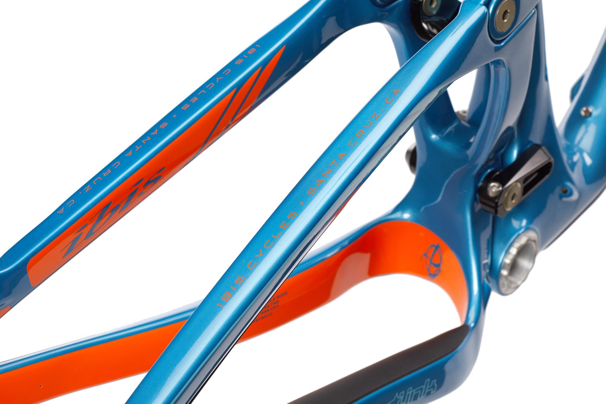 Ibis RipMo: Close-up image of a vibrant blue and orange bike frame, featuring the brand name "Ibis Cycles" and "Santa Cruz, CA" inscribed along the tubing. The frame exhibits a sleek design with smooth lines and a polished finish, highlighting its modern craftsmanship.