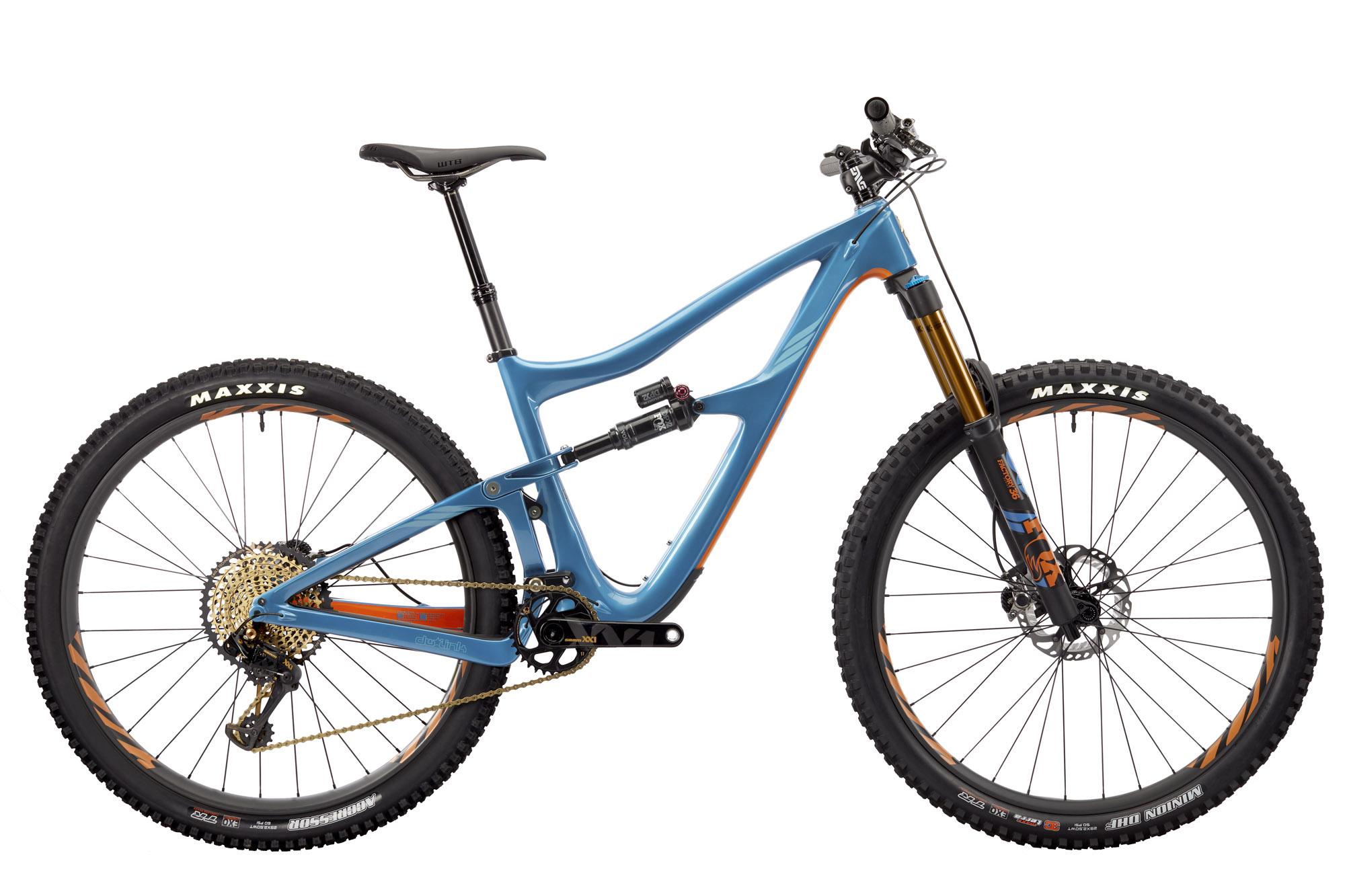 Ibis RipMo: Mountain bike featuring a blue frame, large knobby tires, and high-performance components. The bike has a modern design with a prominent suspension system, adjustable seat post, and details in orange and gold accents. The tires are labeled "MAXXIS," indicating suitability for rugged terrain.