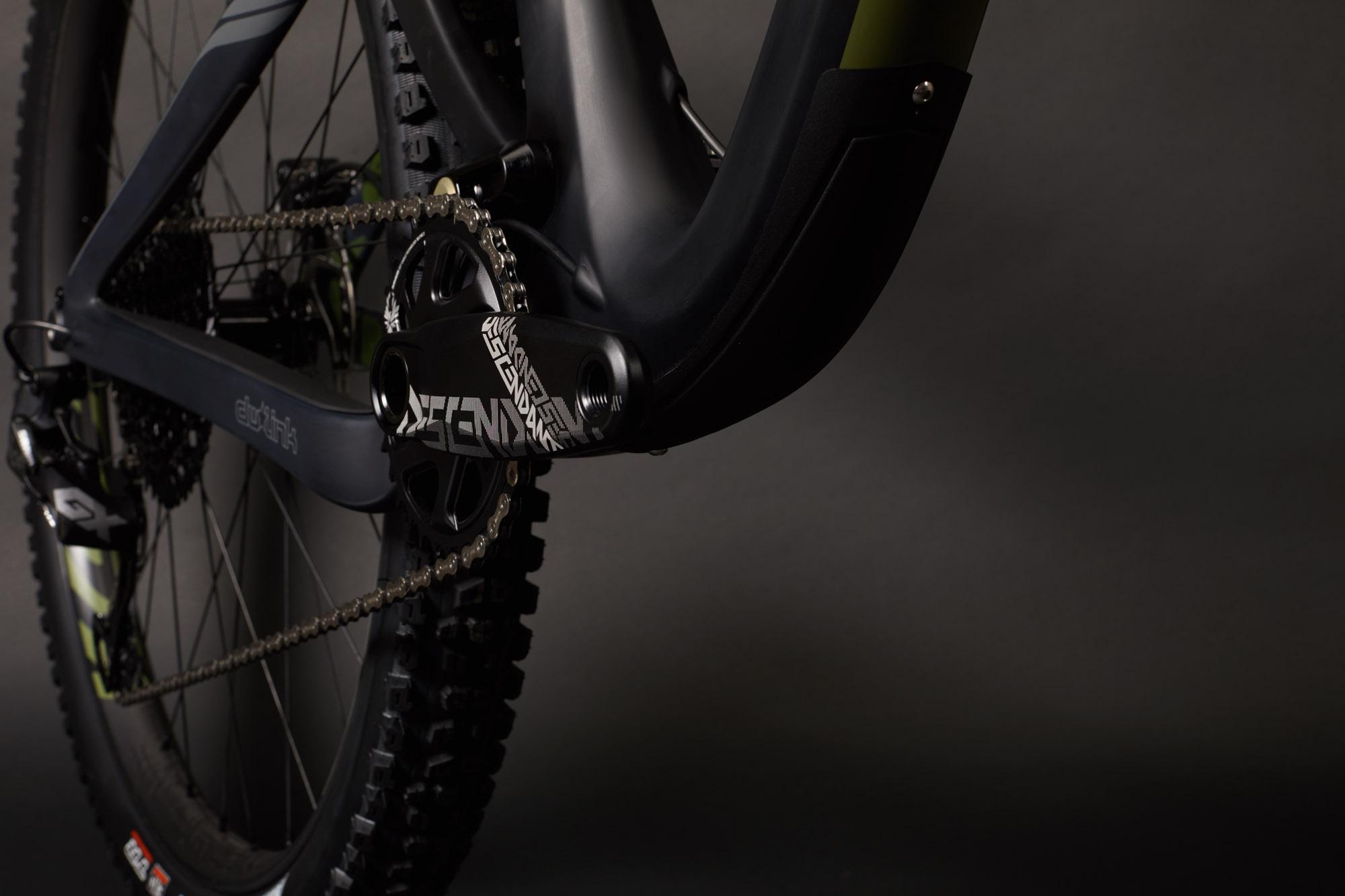 Ibis RipMo: Close-up view of a mountain bike's drivetrain and frame, highlighting the black and green design elements, including the crankset and chain. The image features a dark background that emphasizes the bike's detailing and components.