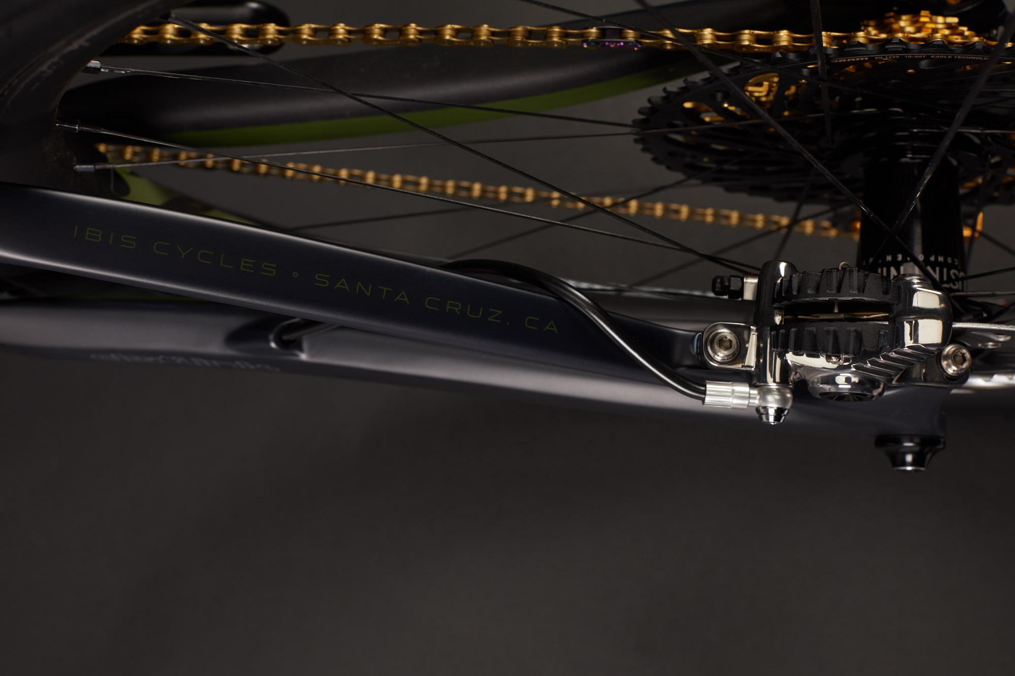 Ibis RipMo: Close-up view of a bicycle frame featuring the text "Ibis Cycles - Santa Cruz, CA," alongside a detailed look at the chain, gears, and braking system, set against a dark background.