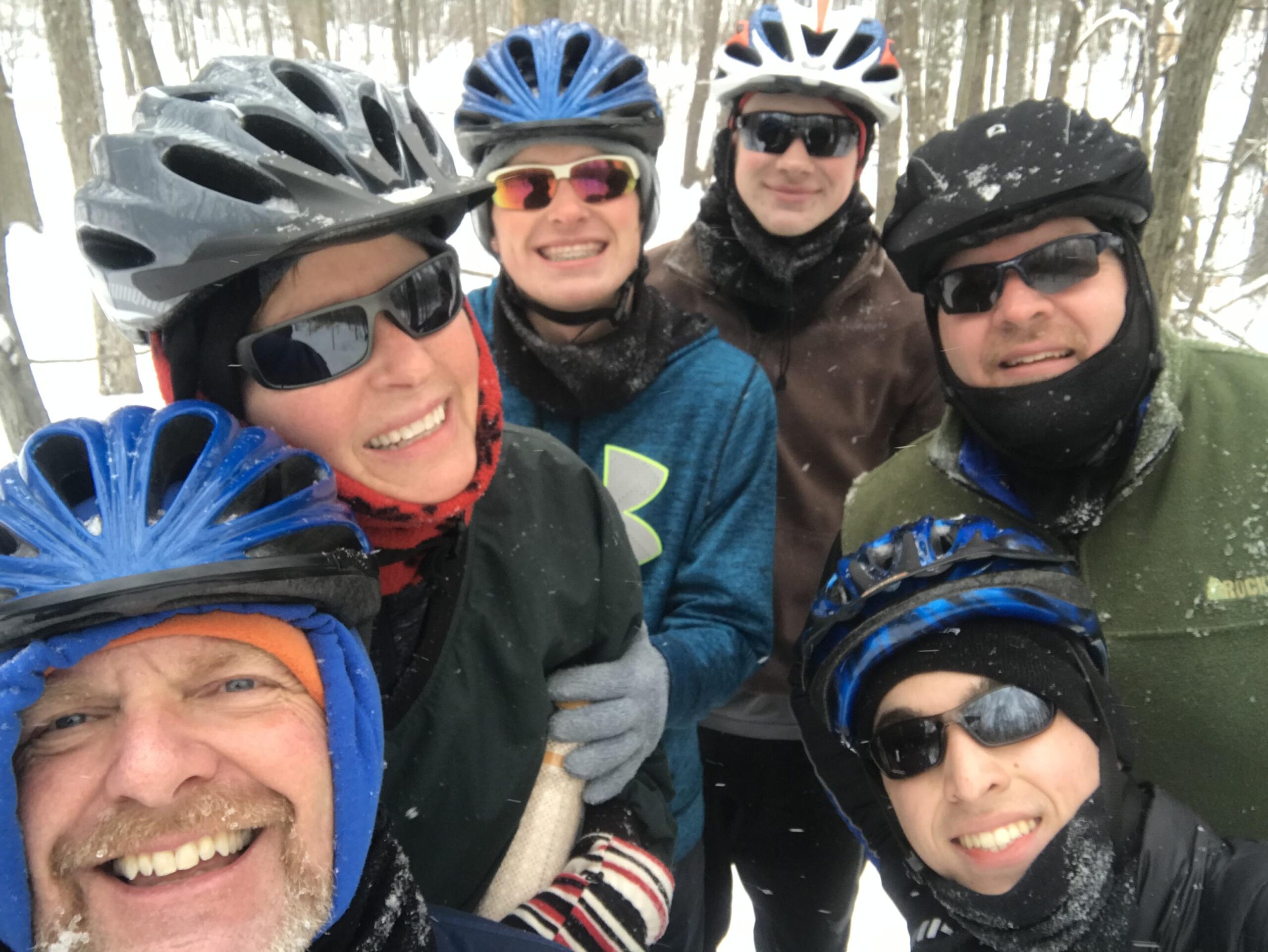 2017 Giant Talon 3: A group of six people wearing winter cycling gear and helmets, smiling for a selfie in a snowy forest. Snow is visible on their clothing and the surrounding trees, suggesting they are enjoying a winter biking adventure.