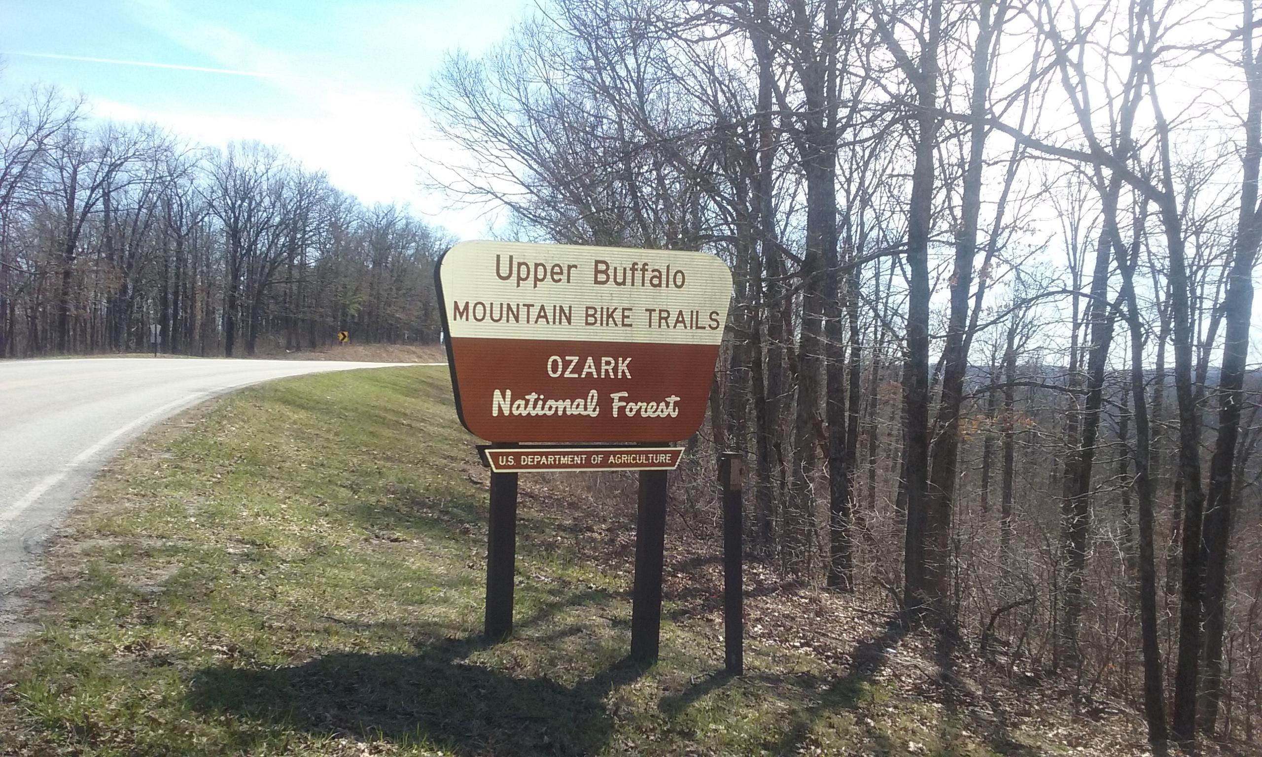 Sign for Upper Buffalo Mountain Bike Trails located in Ozark National Forest, with a winding road and trees in the background. Upper Buffalo Headwaters Trail System mountain bike trail.