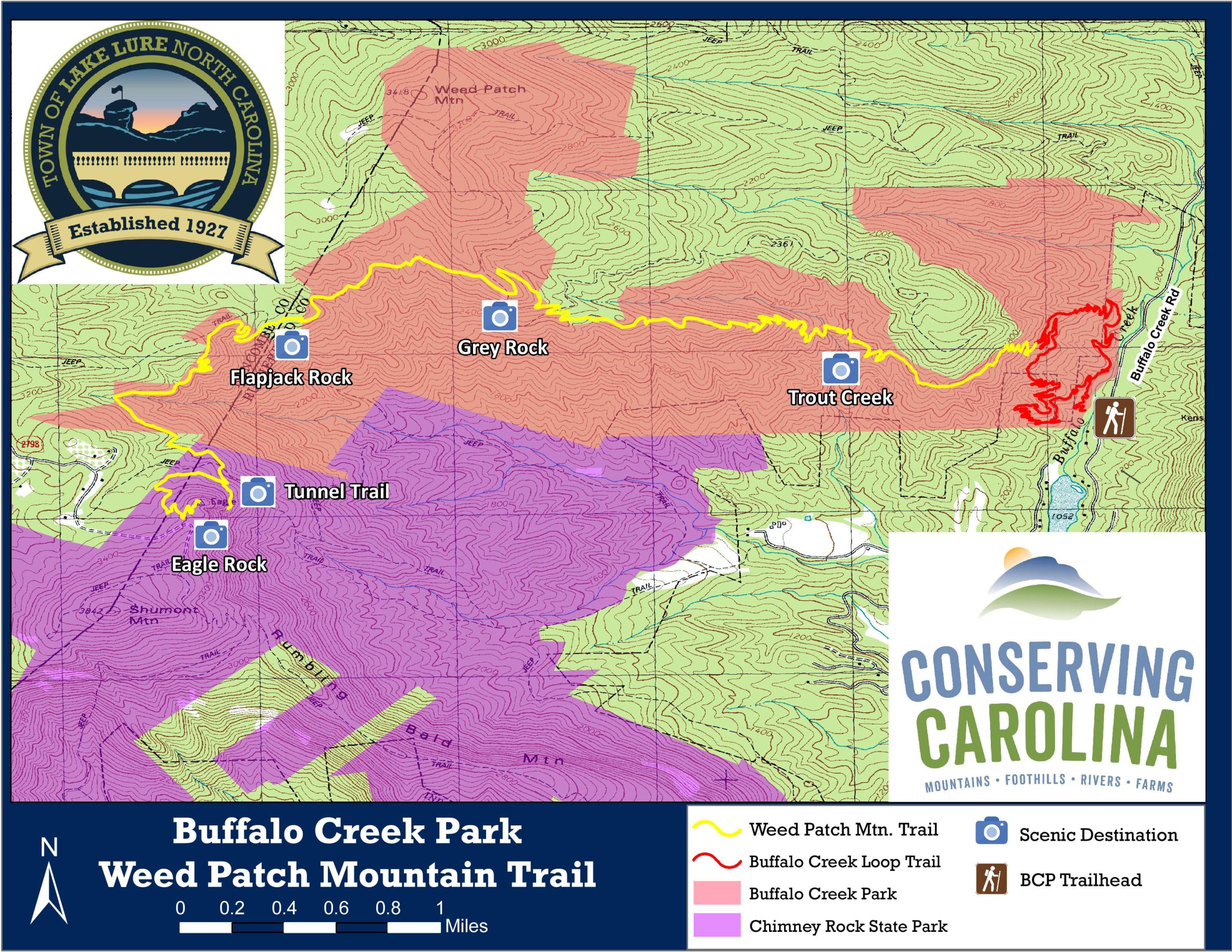 Map of Buffalo Creek Park and the Weed Patch Mountain Trail in Lake Lure, North Carolina. The map features various trails, notable landmarks like Flapjack Rock, Grey Rock, Tunnel Trail, and Eagle Rock, and highlights scenic destinations. Key elements include contour lines, trail markers, and logos for Conserve Carolina and the town of Lake Lure, established in 1927. Weed Patch Mountain Trail mountain bike trail.