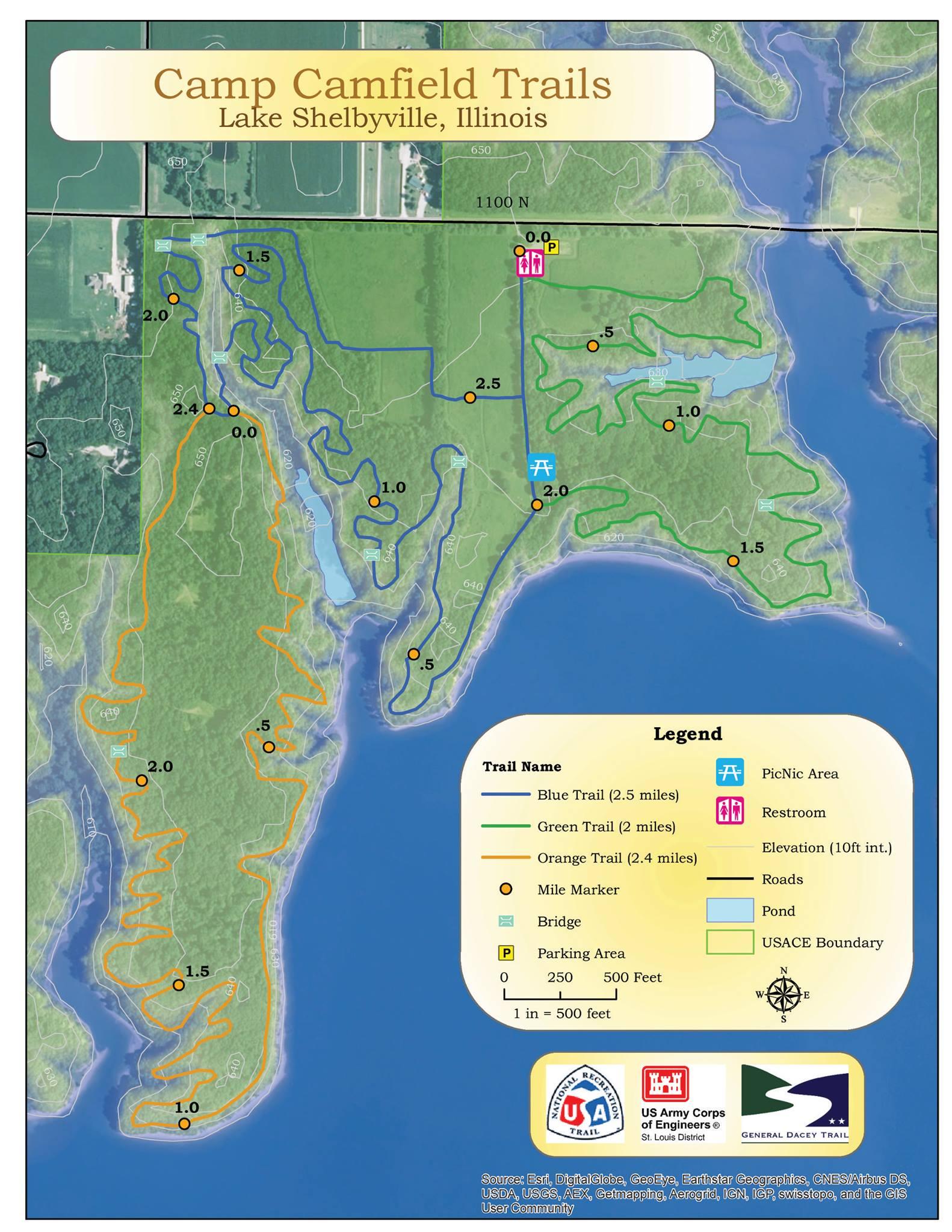 A detailed map of Camp Camfield Trails located at Lake Shelbyville, Illinois, showing various trail lengths marked in blue, green, and orange. The map includes mile markers, parking areas, picnicking spots, restrooms, and elevation details, with boundaries represented. It features a legend for easy navigation, along with a compass rose indicating orientation. Camp Camfield mountain bike trail.