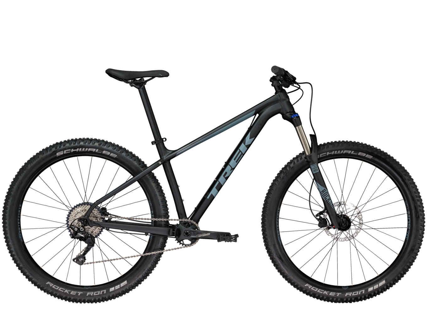 Trek Roscoe 7: A side view of a black and teal Trek mountain bike with wide tires, featuring a front suspension fork and a modern frame design. The bike is equipped with Schwalbe Rocket Ron tires and a Shimano derailleur, positioned on a white background.