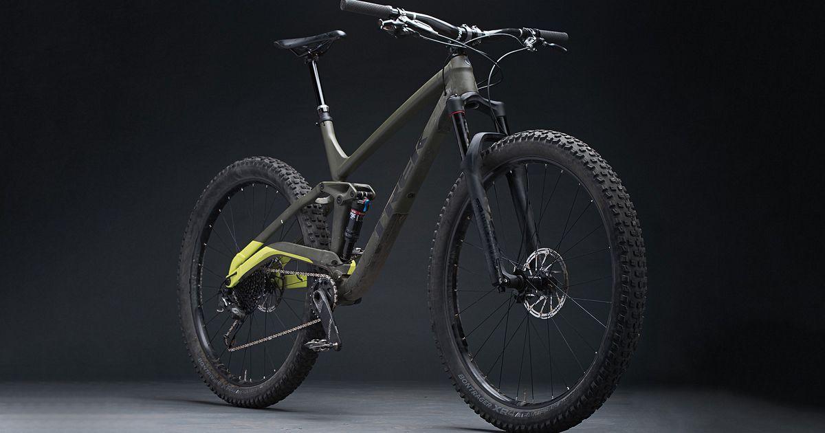 Trek Full Stache: A modern mountain bike with a sleek design featuring a green and black frame, wide tires, and a minimalist aesthetic, displayed against a dark background. The bike emphasizes performance for off-road trails.