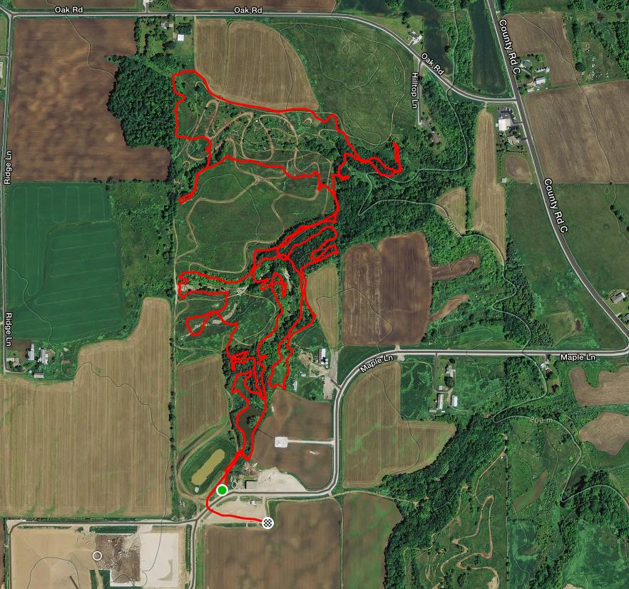 Aerial map showing a detailed trail system outlined in red over agricultural fields and wooded areas, with roads labeled and structures visible, indicating hiking or biking paths in a rural landscape. Riverview Park MTB Trail mountain bike trail.