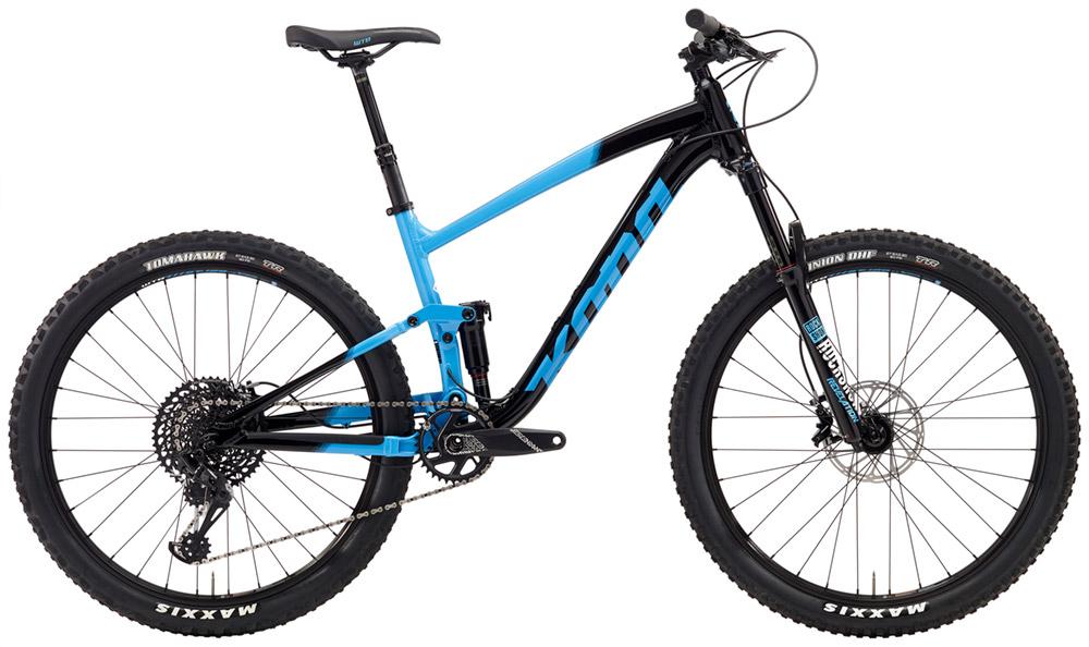 Kona Hei Hei Trail DL: Image of a mountain bike featuring a black and light blue frame, designed for rugged terrains. The bike has wide tires with well-defined treads, a prominent suspension system, and a modern gear setup visible on the rear. The handlebars are straight, adding to its sporty design, and the overall aesthetic highlights a combination of durability and performance for outdoor adventures.