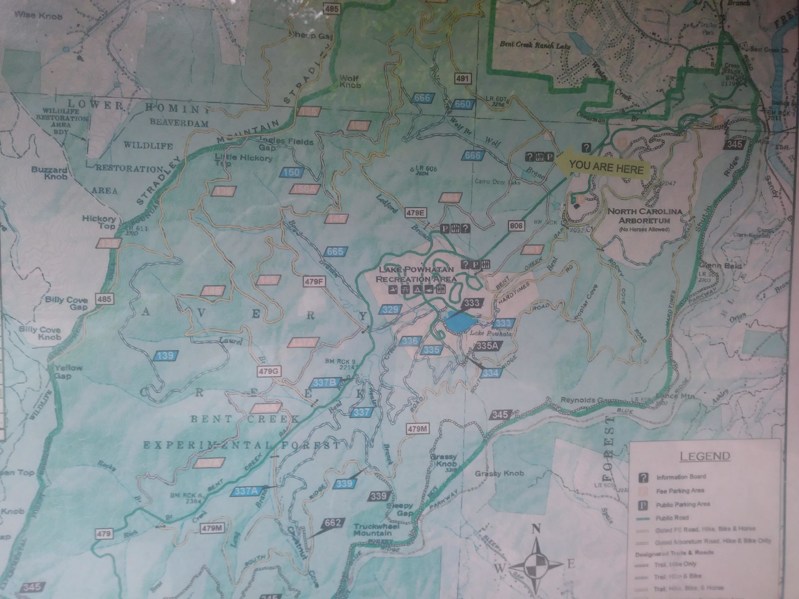 A detailed map of the Bent Creek Experimental Forest area in North Carolina, featuring various labeled trails, parking areas, and landmarks. The map includes a legend for navigation, with a "You Are Here" marker indicating the current location. It shows topographical features, including streams and elevations, with color coding to differentiate between types of areas, such as wildlife restoration and public access points. Bent Creek mountain bike trail.
