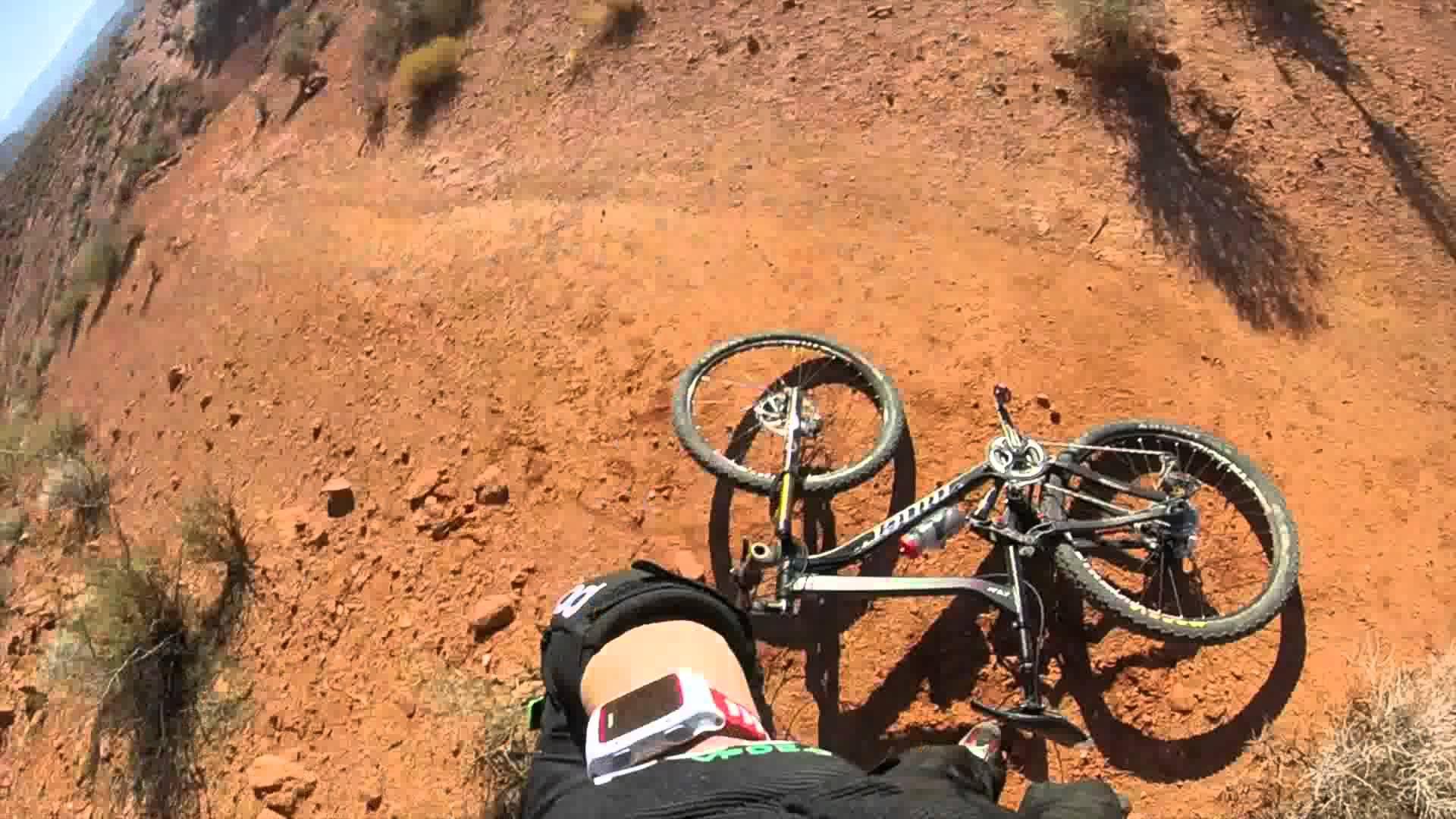 A view from above showing a mountain bike lying on its side on a dirt trail, with a person