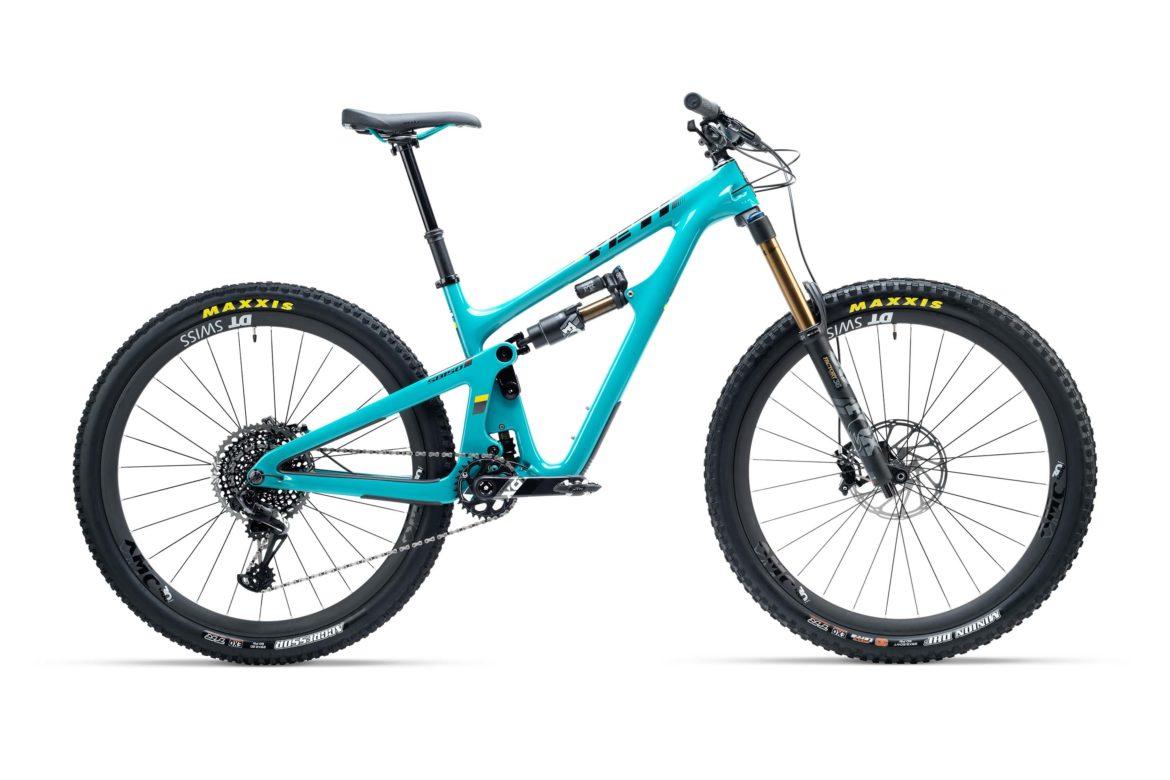Yeti SB150: A turquoise mountain bike with a lightweight frame, featuring a suspension system, wide tires with Maxxis branding, and a Shimano drivetrain. The bike is shown from a side view against a white background, emphasizing its sleek design and components.
