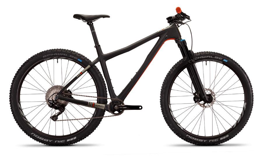 Ibis DV9: A sleek black mountain bike with a lightweight carbon frame, featuring wide, knobby tires and a front suspension fork. The bike has a minimalist design with colorful accents on the frame and a visible gear system. Ideal for off-road riding and mountain biking.