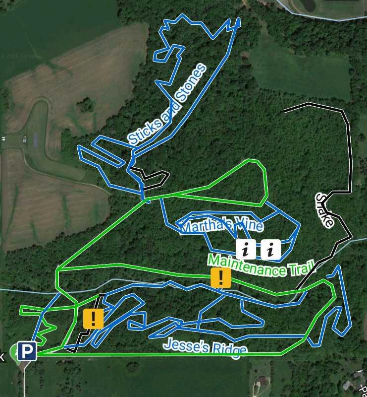 Map of a trail system with designated paths labeled in blue and green, including "Sticks and Stones," "Martha's Vine," "Maintenance Trail," and "Jesse's Ridge," along with parking and caution symbols indicating points of interest or warnings. The map features wooded areas and nearby open fields. FDR Park mountain bike trail.