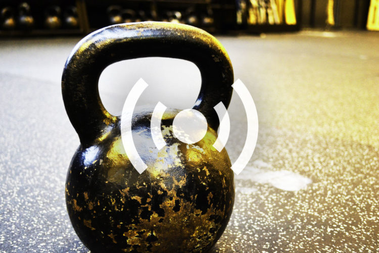 A close-up of a worn black kettlebell resting on a textured gym floor, with a blurred background of exercise equipment. A circular graphic with radiating lines overlays the kettlebell, suggesting movement or sound.