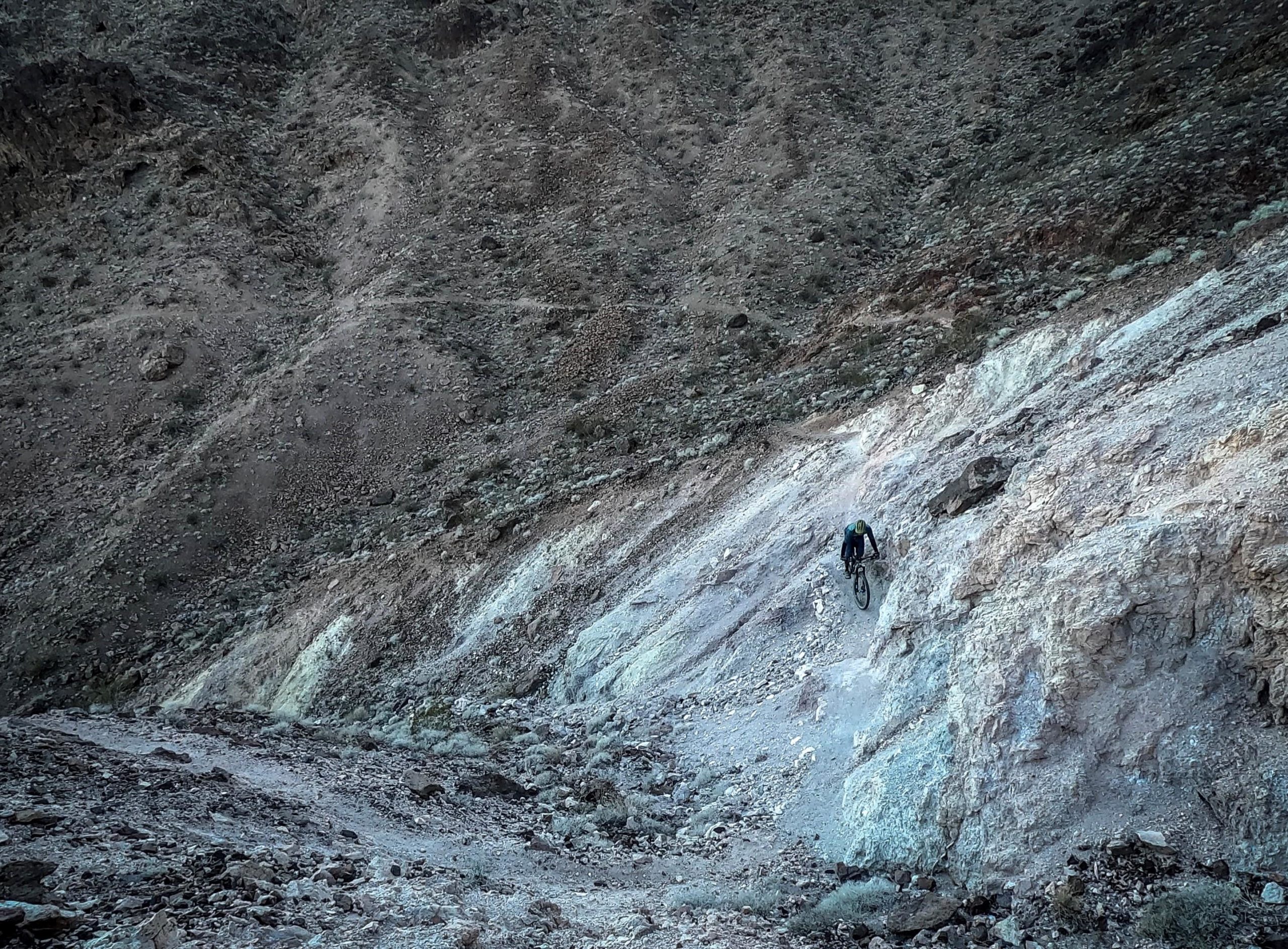 A mountain biker navigates a steep, rocky terrain, showcasing skill and determination against a backdrop of rugged, earthy hills. Bootleg Canyon mountain bike trail.