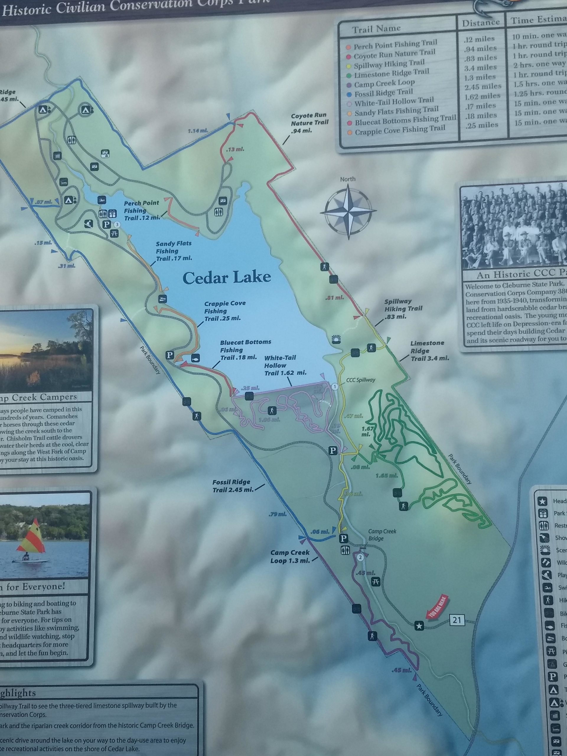 Map of Historic Civilian Conservation Corps Park featuring trails and areas around Cedar Lake. Includes details on various hiking and fishing trails, such as distances and estimated times, with marked locations for amenities and scenic highlights. A compass rose indicates north, and the map emphasizes outdoor activities like biking, boating, and wildlife watching. Cleburne State Park mountain bike trail.
