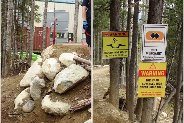 Image of a mountain biking trail featuring a rocky jump area on the left, with a portion of a forest in the background. On the right, there are multiple warning signs indicating potential injury risks, requiring protective gear, and stating that the trail is advanced and not suitable for beginners or intermediate riders.