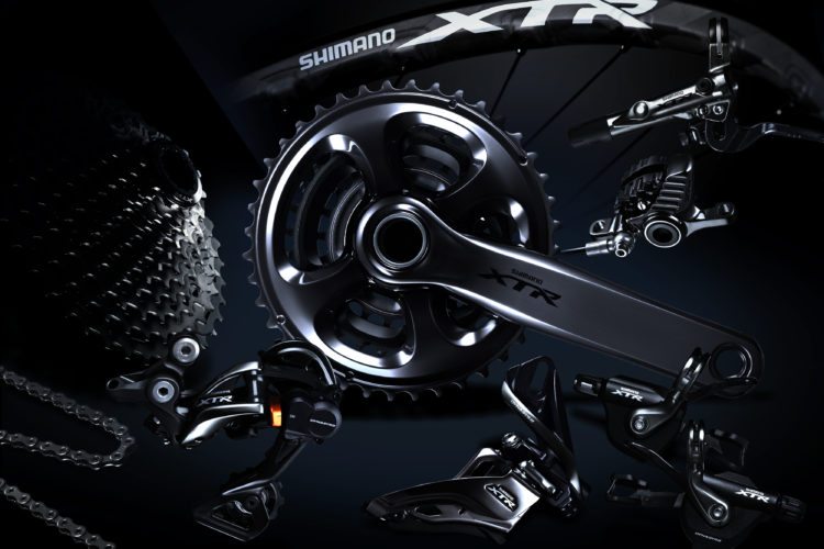 Alt text: A collection of Shimano XTR bicycle components arranged artistically, including a crankset, derailleur, chain, and cassette, all displayed against a dark background to emphasize their sleek design.