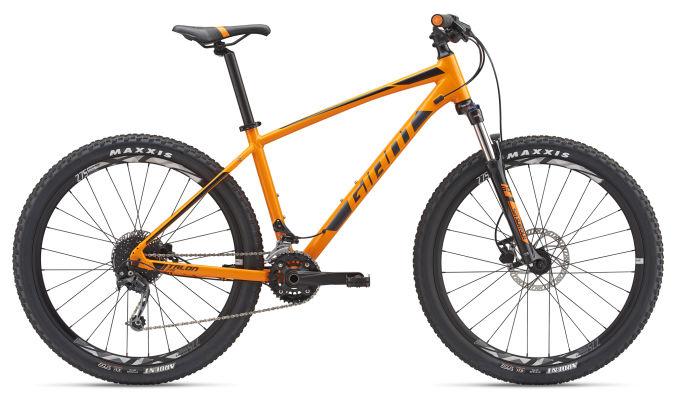 Giant Trance: Mountain bike in vibrant orange with black accents, featuring a sturdy frame, wide tires, and disc brakes, positioned against a neutral background.