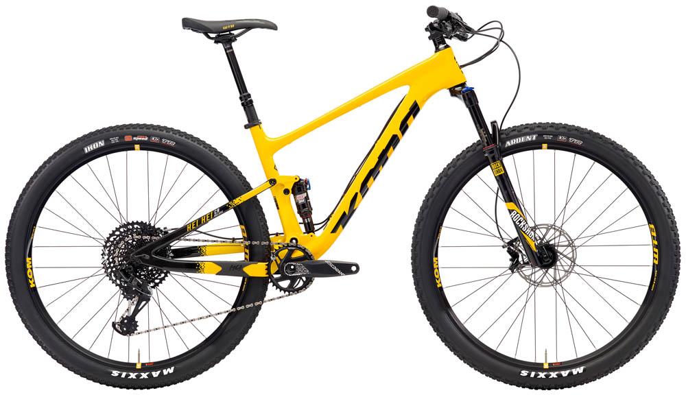 Kona Hei Hei: A bright yellow mountain bike with a modern frame design and large black tires, featuring a suspension fork, disc brakes, and a gear shifter. The bike is positioned in profile against a neutral background.