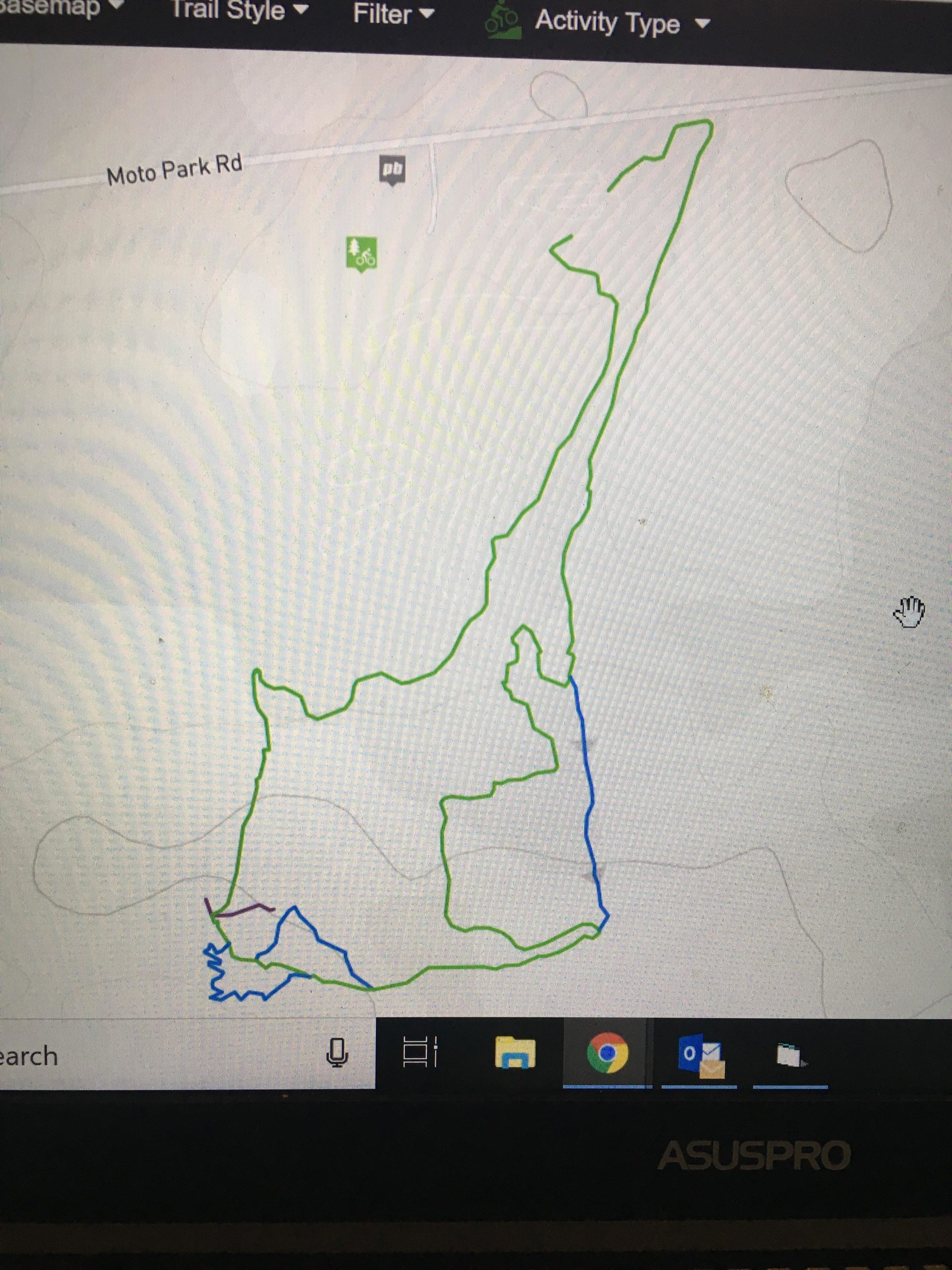 A digital map displaying two distinct routes. One route is highlighted in green and runs primarily vertical and vertical zigzag, while the other is shown in blue with a more rounded shape. The map indicates a trail system near Moto Park Road, featuring outdoor activity icons. MotoPark MTB and Saugeen Conservation Lands mountain bike trail.