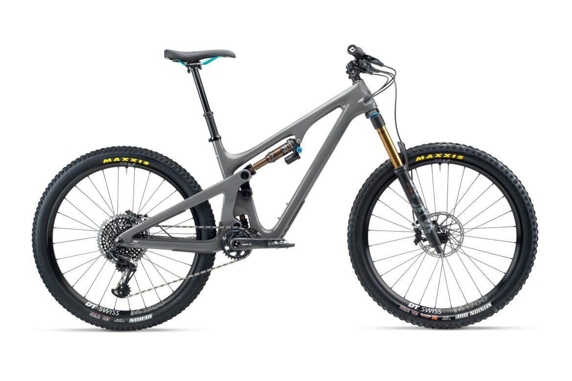 Yeti SB140: A sleek gray mountain bike with a full suspension design, featuring a prominent shock absorber, hydraulic disc brakes, and equipped with Maxxis tires. The bike is positioned against a white background, showcasing its modern frame and high-performance components.