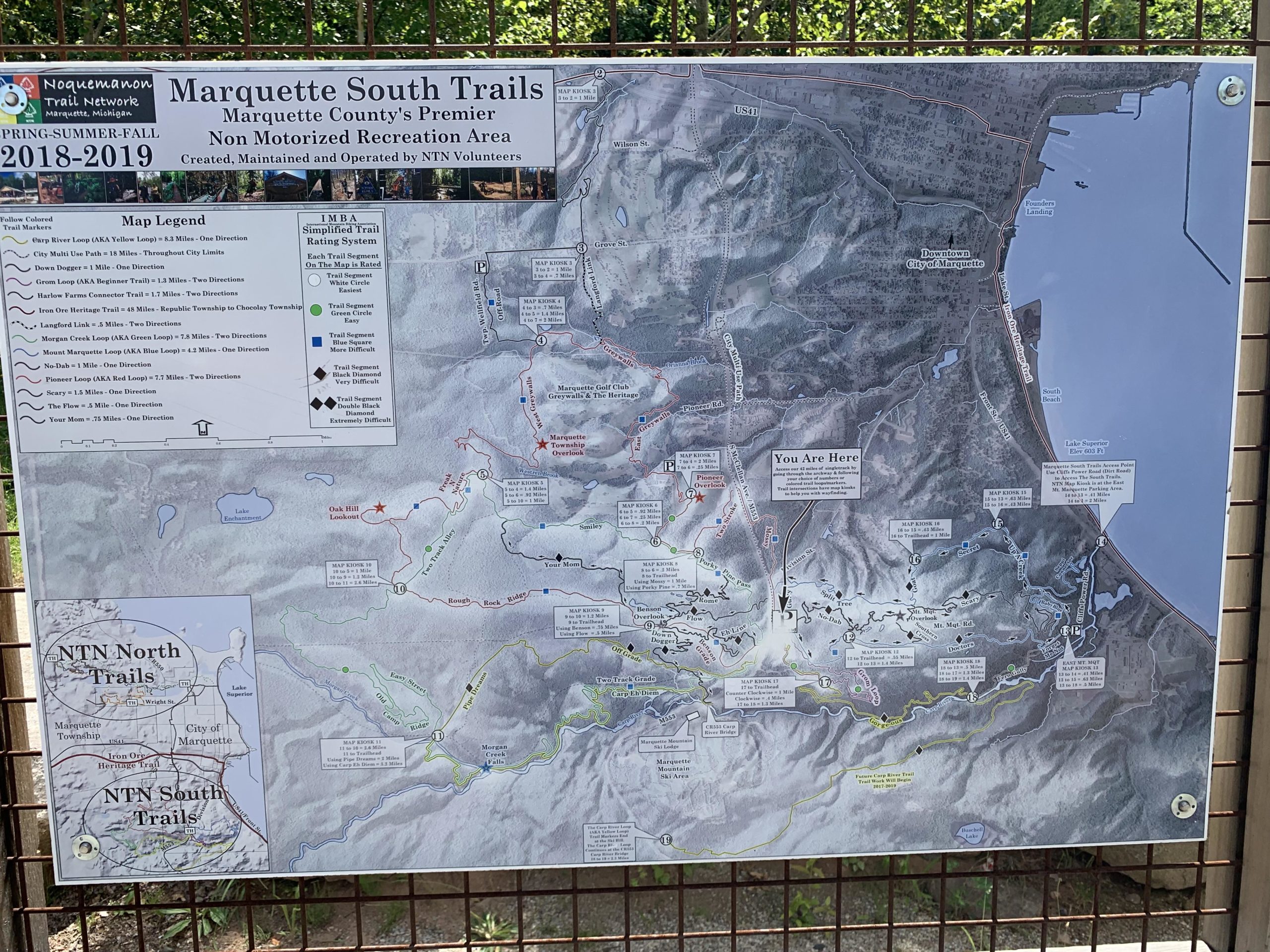 Map of the Marquette South Trails, a non-motorized recreation area in Marquette County. The map includes various trails colored according to difficulty levels, a legend explaining trail types, and locations of trail heads. Includes a "You Are Here" marker to assist with navigation, along with notable landmarks and proximity to downtown Marquette. Noquemanon Trails Network: South Marquette Trails mountain bike trail.