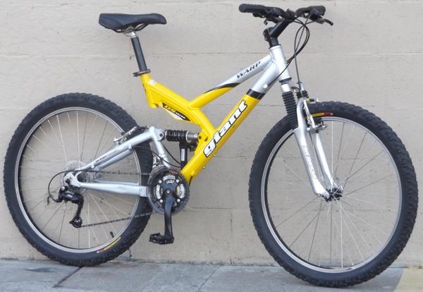 Giant Warp DS3: A yellow and silver mountain bike leaning against a light-colored wall. The bike features thick tires, a front suspension fork, and a prominent "Giant" branding on the frame.