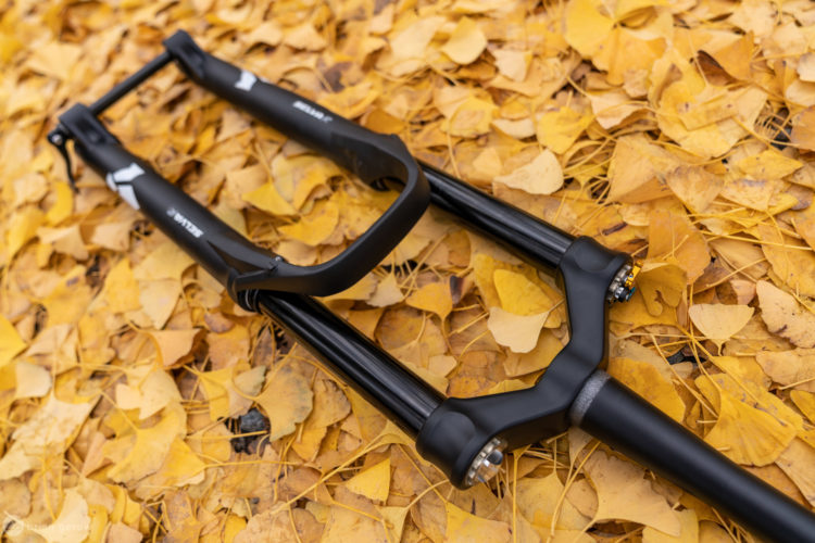 A black bicycle fork resting on a bed of yellow autumn leaves, showcasing its sleek design and components.