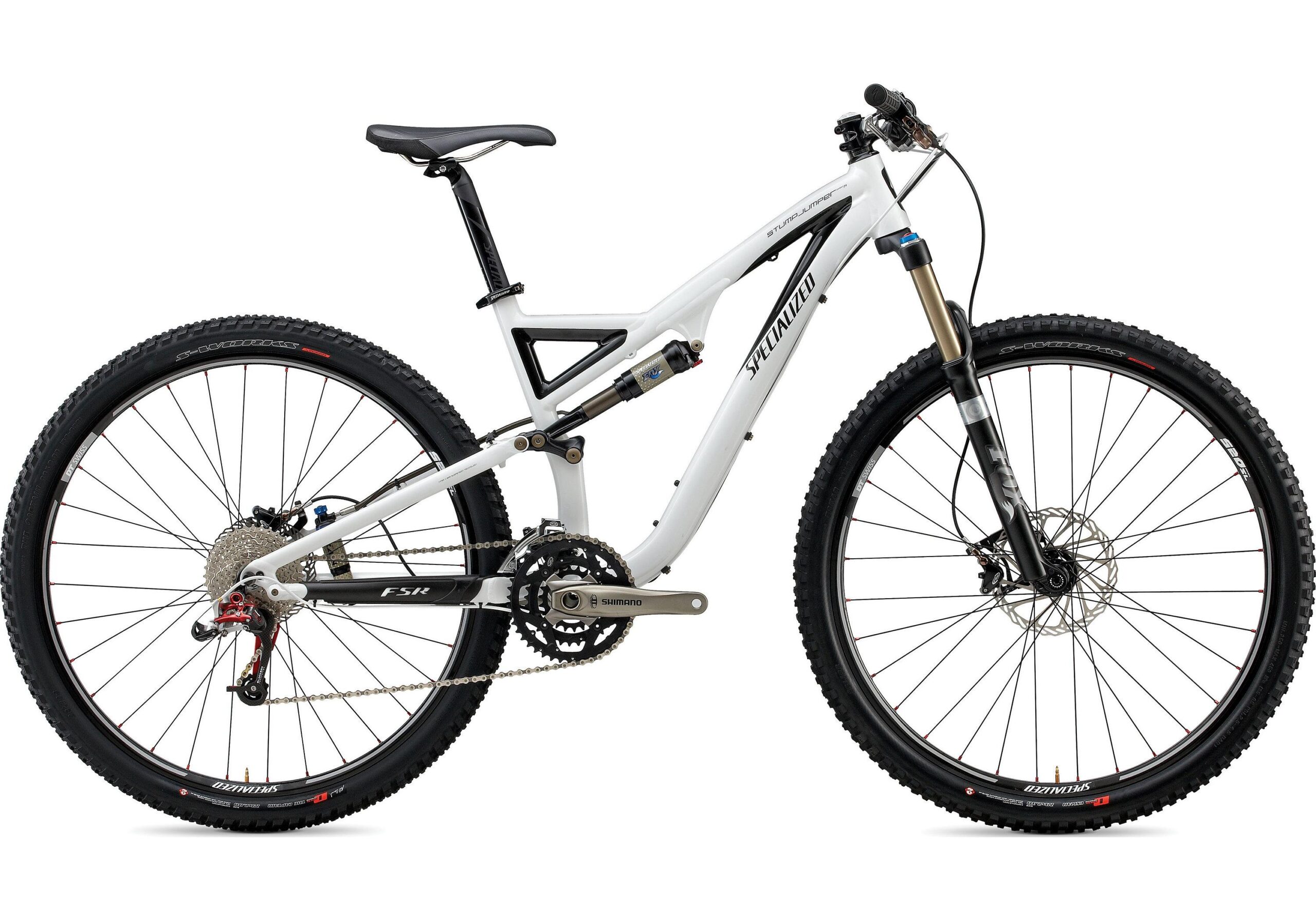 Specialized Stumpjumper FSR 29: A mountain bike with a white frame, featuring front suspension forks and wide tires. The bike has a Shimano drivetrain and prominent disc brakes. The seat is raised, and the bike is shown from a side angle against a plain background.