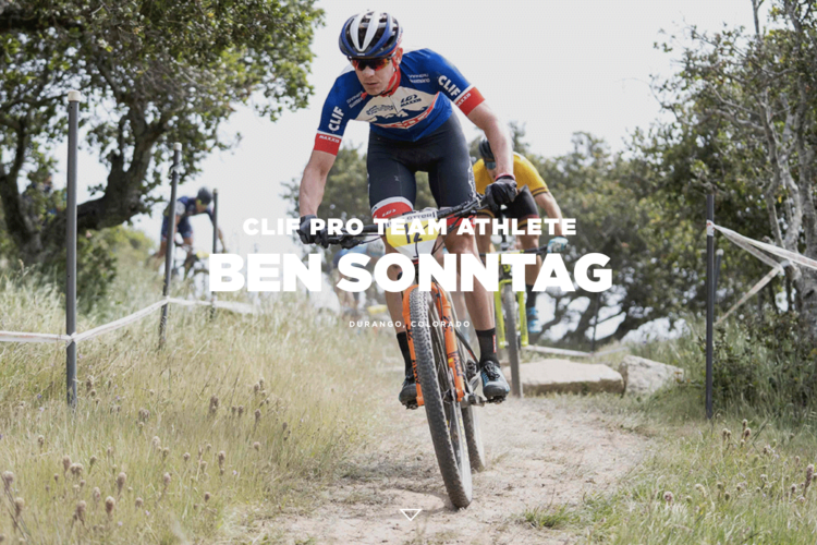 Image of a mountain bike racer, identified as Ben Sonntag, navigating a trail in Durango, Colorado. The athlete is wearing a blue and red cycling jersey with "CLIF" branding, focusing on the path ahead as he rides past greenery and other racers in the background.