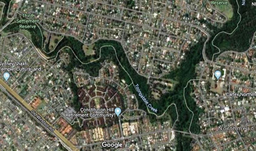 A satellite view of a suburban area featuring residential neighborhoods, the Toongabbie Creek, and nearby landmarks such as the Constitution Hill Retirement Community and various parks and reserves. Major roads and local businesses are also visible. Pemulwuy mountain bike trail.