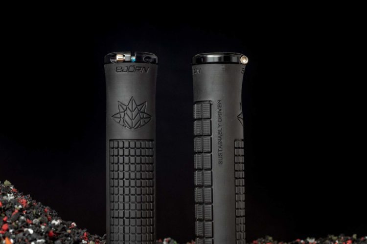 Two black lighters with textured grips and embossed logos are positioned against a dark background, surrounded by a textured surface made of colorful bits, suggesting a sustainable or recycled material.