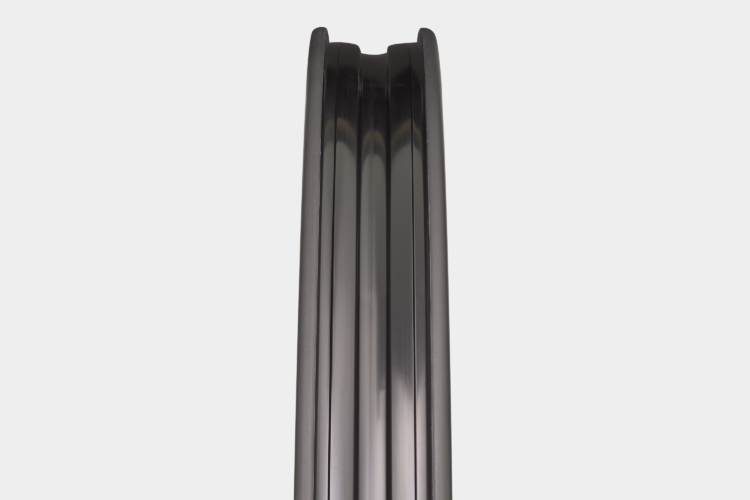 A close-up view of a sleek, black bicycle rim, showcasing its smooth curves and polished finish. The rim features multiple parallel grooves, emphasizing its design and structure. The background is plain and white, highlighting the rim's sleek appearance.