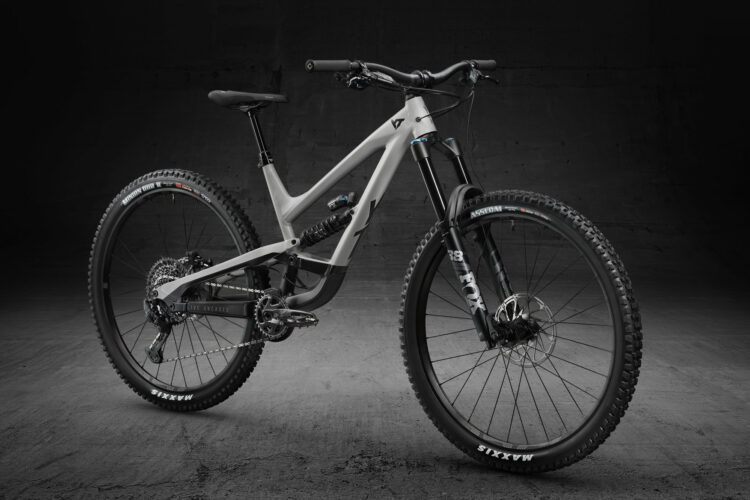 A modern mountain bike displayed against a dark background, showcasing its sleek and robust design. The bike features a gray frame, notable suspension components, and knobby tires suitable for off-road terrain. The image highlights the bike's intricate details, including the gears, brakes, and handlebars.