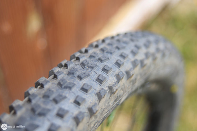 Close-up of a textured bicycle tire showcasing its rugged tread pattern against a blurred wooden background.