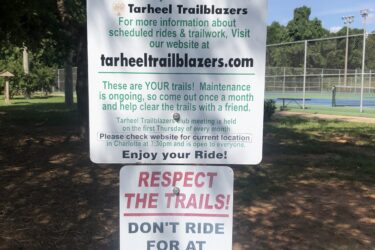 A sign at Renaissance Park detailing the mountain bike trails maintained by Tarheel Trailblazers. The sign highlights trail maintenance and encourages community involvement, stating that riders should respect the trails and avoid riding for at least 24 hours after rainfall. Renaissance Park mountain bike trail.