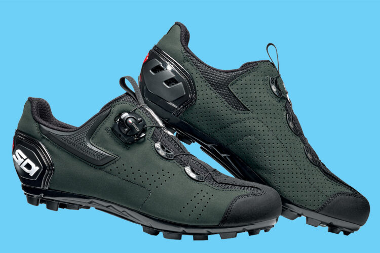 A pair of dark green cycling shoes with a perforated design and black accents. The shoes feature a BOA dial closure system for a secure fit and have rugged soles suitable for off-road cycling. The background is a bright blue color.