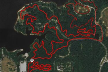 A map showing a network of trails marked in red on a satellite image of a forested area with a lake, featuring winding paths and intersections, labeled "Markum Branch Rd" at the bottom. Rend Lake Mountain Bike Trail mountain bike trail.