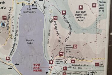 Map of Devil's Lake State Park featuring various trails, landmarks, and facilities. Key locations include Devil's Head, Boardwalk, and visitor center. The map indicates different trails with their distances and a “You Are Here” marker. Standing Rocks mountain bike trail.