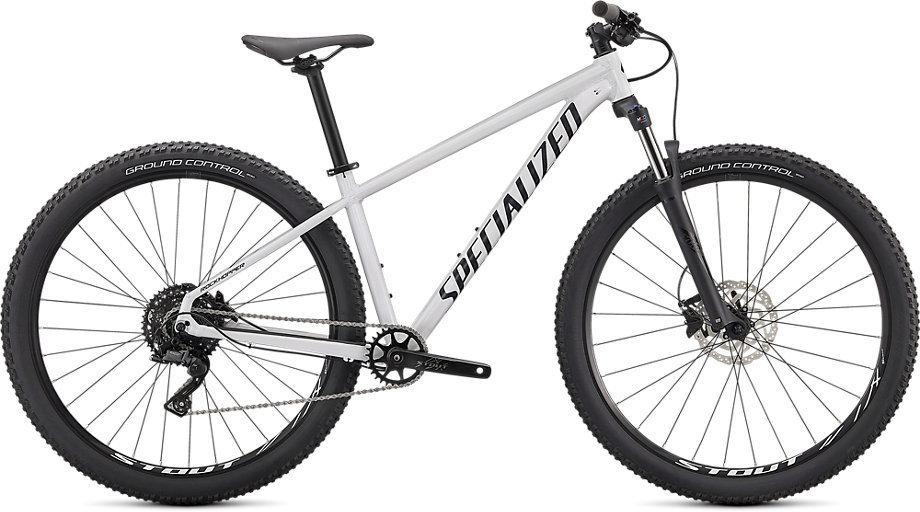 Specialized Rockhopper Comp 29: A white mountain bike with a sleek design, featuring wide tires and a prominent brand name "SPECIALIZED" on the frame. The bike is equipped with front suspension and has a single gear system, suitable for off-road riding.