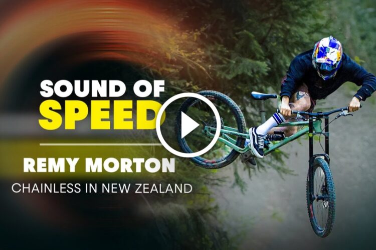A mountain biker performing a jump on a green bike in a forested area, with the text overlay "Sound of Speed" and "Remy Morton, Chainless in New Zealand." A play button is centered on the image, indicating it is a video thumbnail.