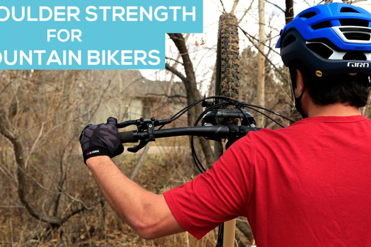 A mountain biker in a red shirt and blue helmet is holding a bicycle upright, emphasizing shoulder strength. The background features bare trees, suggesting an outdoor setting. Text at the top reads "Shoulder Strength for Mountain Bikers."